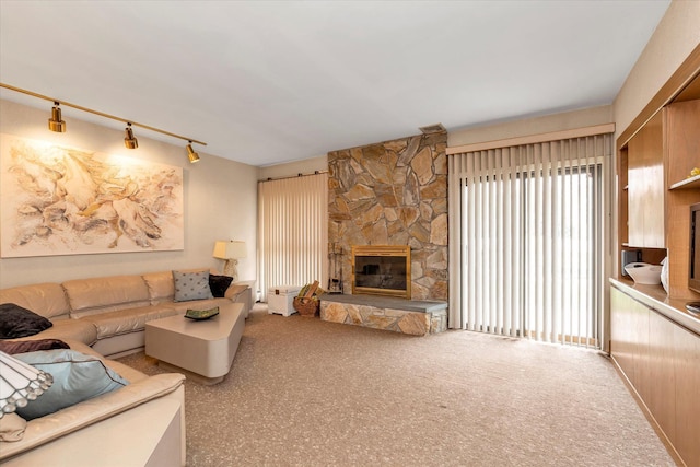 living room featuring rail lighting, a stone fireplace, and carpet