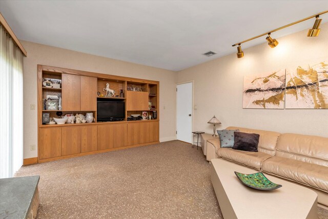 living area with track lighting, visible vents, and baseboards
