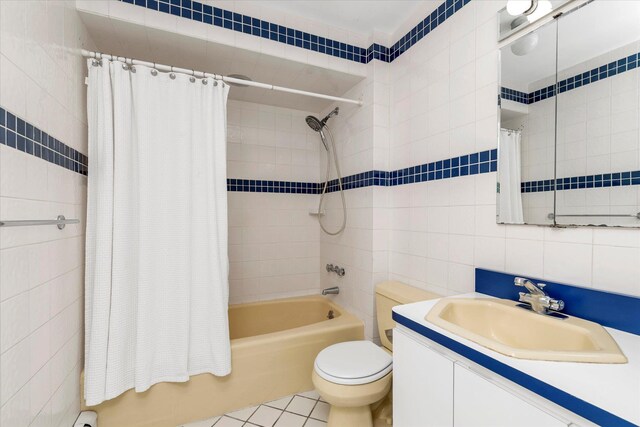 bathroom featuring tile walls, vanity, shower / bathtub combination with curtain, and toilet