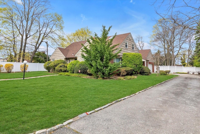 view of home's exterior with a yard, driveway, fence, and roof with shingles
