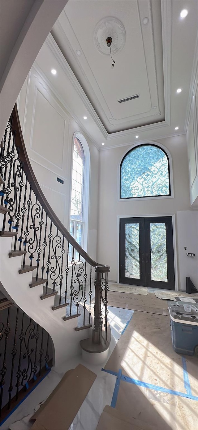 entrance foyer featuring stairway, crown molding, french doors, a towering ceiling, and visible vents