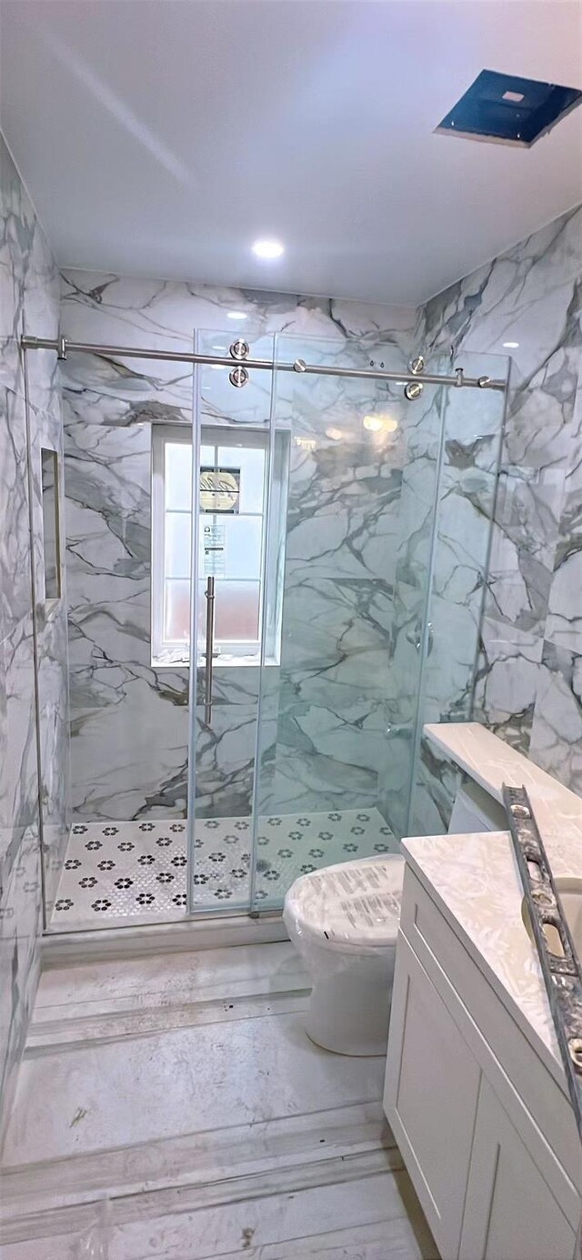 full bath featuring toilet, vanity, and a marble finish shower