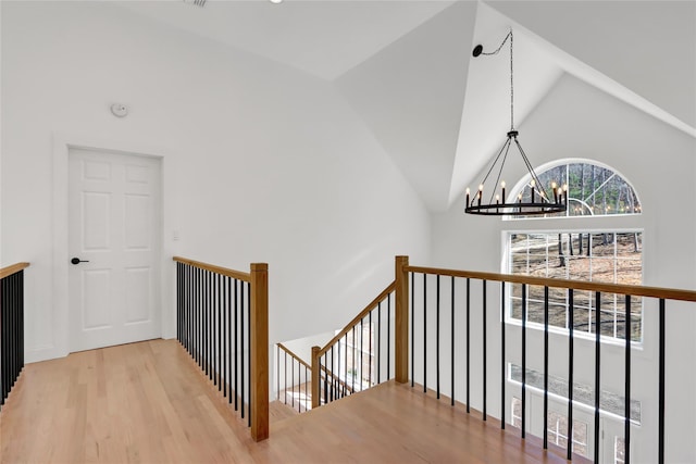 interior space featuring high vaulted ceiling, wood finished floors, a notable chandelier, and an upstairs landing