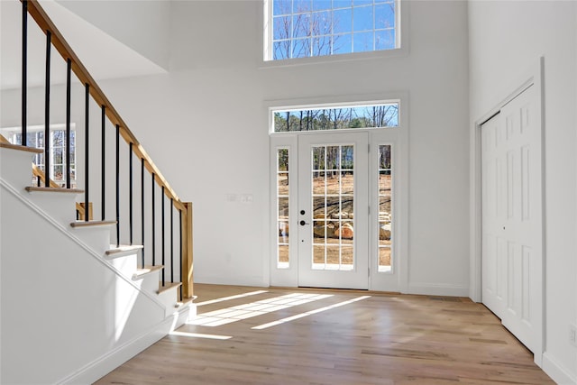 entryway featuring a towering ceiling, stairs, wood finished floors, and baseboards