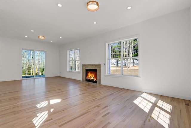unfurnished living room with light wood-type flooring, recessed lighting, and a high end fireplace