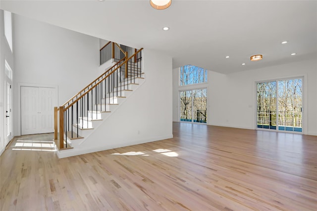 unfurnished living room featuring stairway, recessed lighting, baseboards, and light wood-type flooring