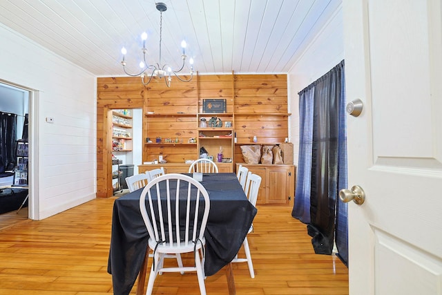 dining area with light wood-type flooring, wood walls, wooden ceiling, and an inviting chandelier