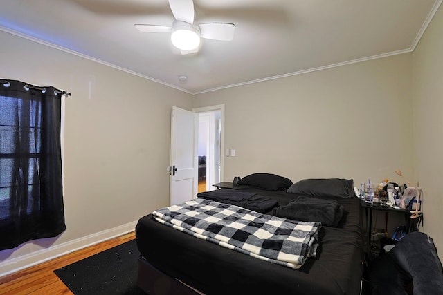 bedroom with wood finished floors, crown molding, baseboards, and a ceiling fan