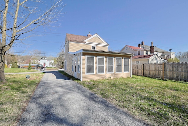 back of house featuring a lawn, fence, and driveway
