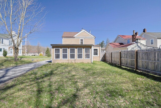 rear view of house with a yard and fence