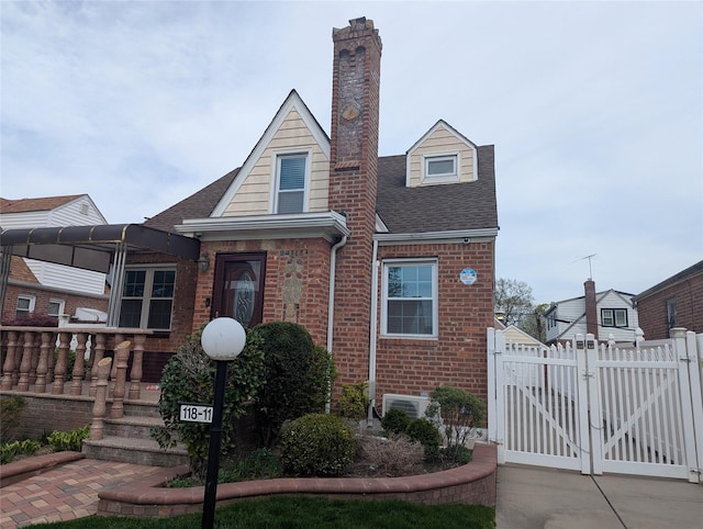 view of front of house featuring fence, a chimney, brick siding, a gate, and a shingled roof