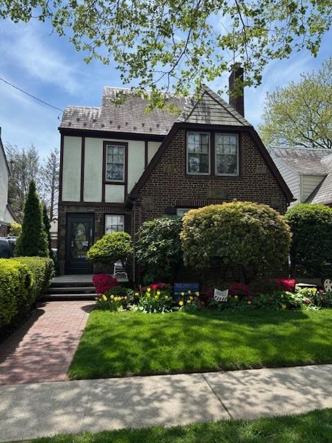 236 Crocus Ave, Floral Park, NY 11001 - tudor house with stucco siding, a chimney, and a front yard