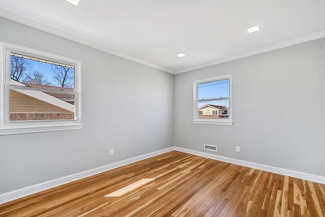 spare room featuring baseboards, crown molding, wood finished floors, and visible vents