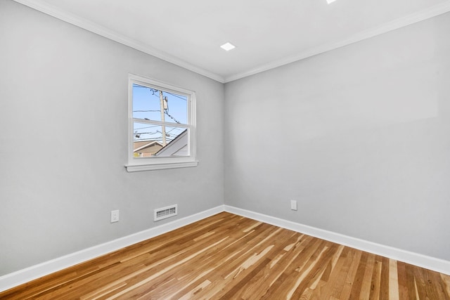spare room with visible vents, light wood-style flooring, baseboards, and ornamental molding