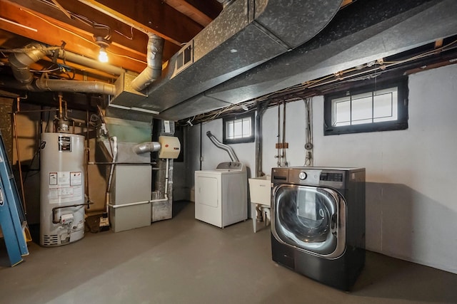 basement with washing machine and dryer, heating unit, gas water heater, and a sink