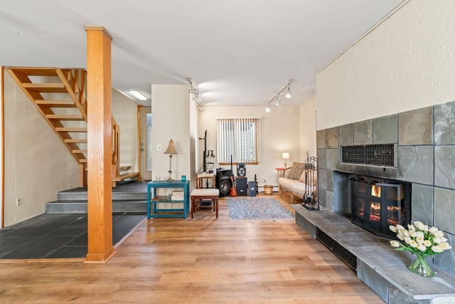 living room featuring wood finished floors, a fireplace, stairs, and rail lighting