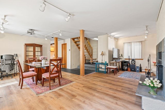 dining room with light wood-style flooring, rail lighting, stairs, and ceiling fan