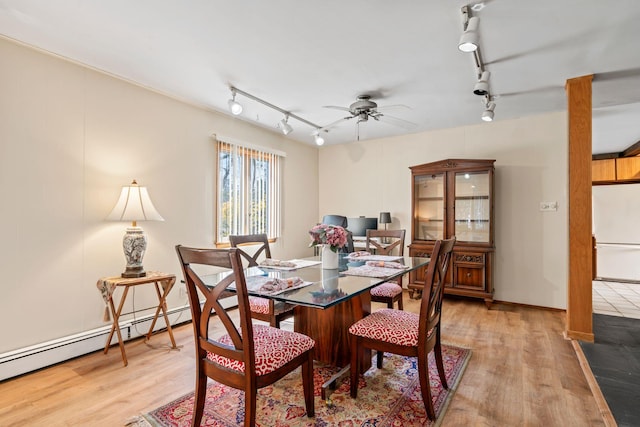 dining space featuring baseboard heating, rail lighting, a ceiling fan, and light wood-style flooring
