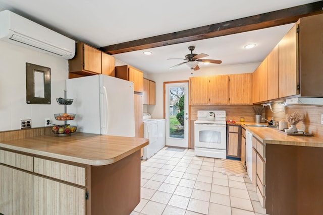 kitchen featuring washer and clothes dryer, a sink, light tile patterned flooring, a wall mounted AC, and white appliances