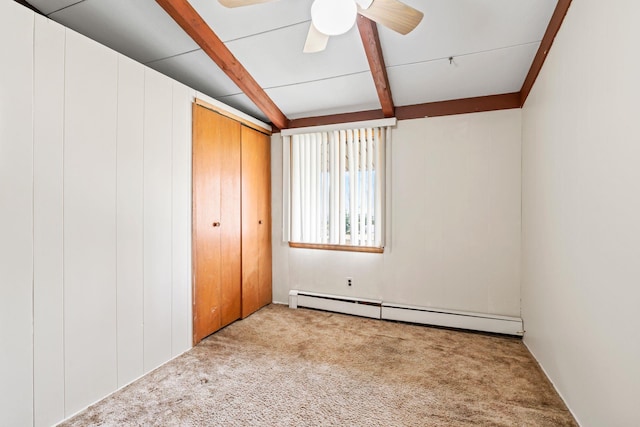 unfurnished bedroom featuring baseboard heating, ceiling fan, beam ceiling, and carpet