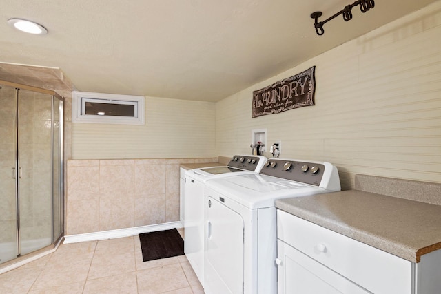 clothes washing area featuring cabinet space, tile walls, light tile patterned floors, and separate washer and dryer