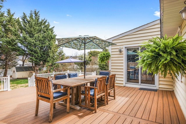 deck featuring an outdoor structure, outdoor dining space, and a storage shed