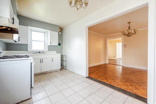 kitchen featuring baseboards, a chandelier, white cabinetry, white range with gas cooktop, and light countertops