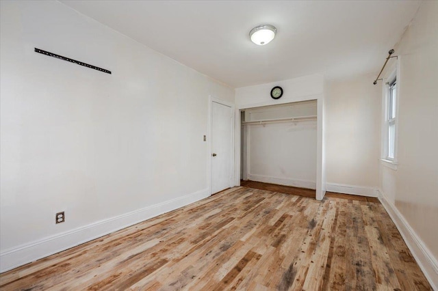 unfurnished bedroom featuring light wood finished floors, baseboards, and a closet