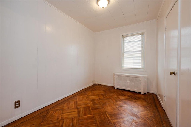 spare room with crown molding, baseboards, and radiator