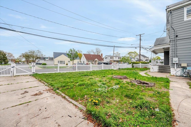 view of yard featuring a gate, a residential view, fence private yard, and an outdoor fire pit