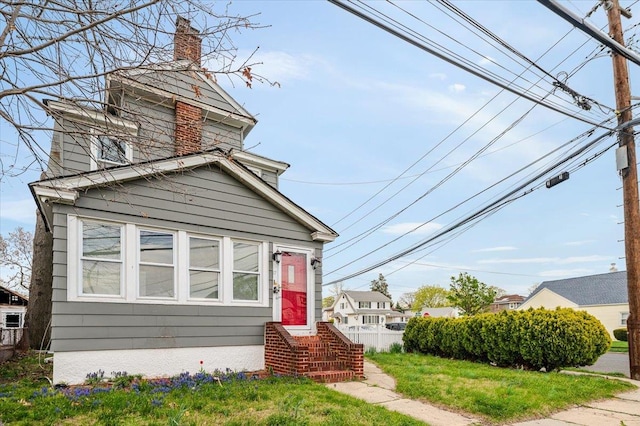 view of front of house with fence, a front lawn, and a chimney