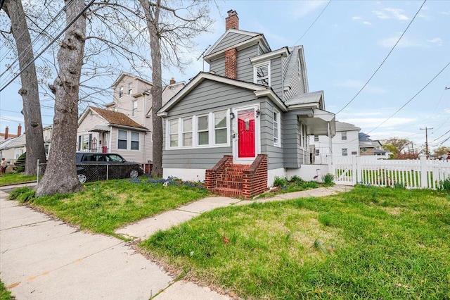 bungalow-style house with a chimney, fence, and a front yard