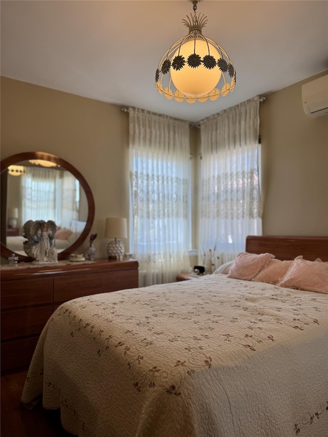 bedroom with a wall unit AC and wood finished floors