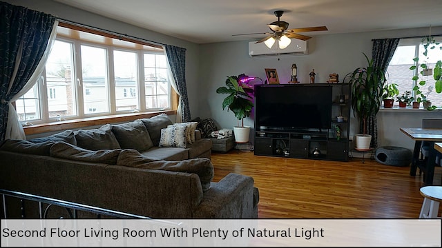 living room featuring a ceiling fan, wood finished floors, and a wall unit AC