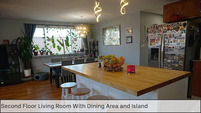 kitchen with wooden counters, stainless steel fridge with ice dispenser, wood finished floors, a kitchen island, and a notable chandelier