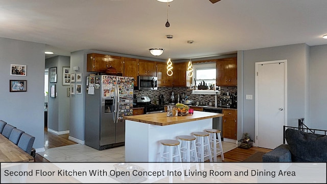 kitchen featuring stainless steel appliances, backsplash, a kitchen island, pendant lighting, and butcher block countertops