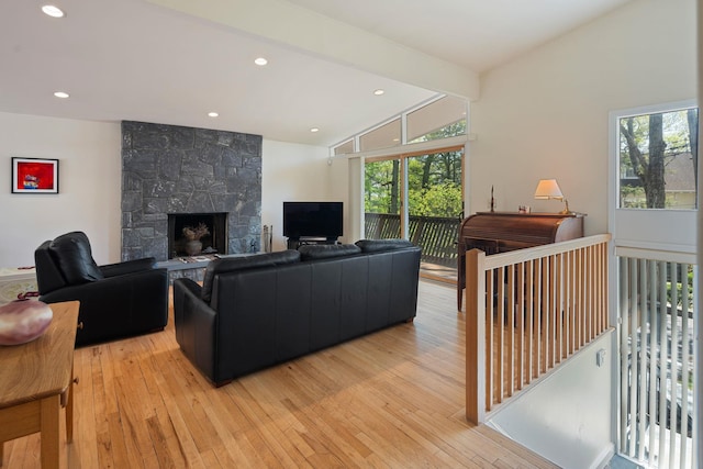 living area featuring a fireplace, lofted ceiling with beams, plenty of natural light, and light wood-style floors