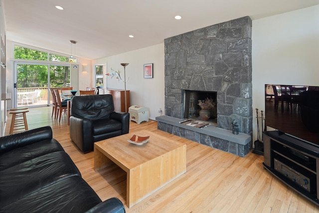 living room featuring lofted ceiling, a fireplace, and wood finished floors