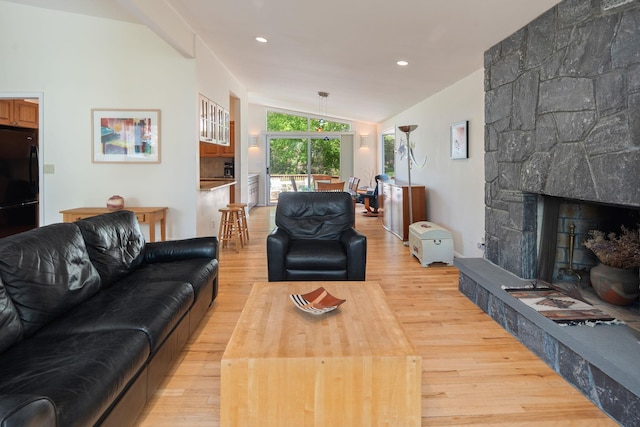 living room with lofted ceiling, a stone fireplace, recessed lighting, and light wood-type flooring
