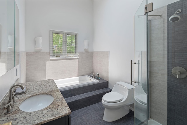 bathroom with a garden tub, toilet, a stall shower, tile walls, and vanity