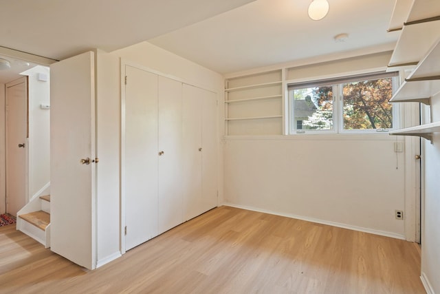 unfurnished bedroom featuring baseboards, light wood finished floors, and a closet