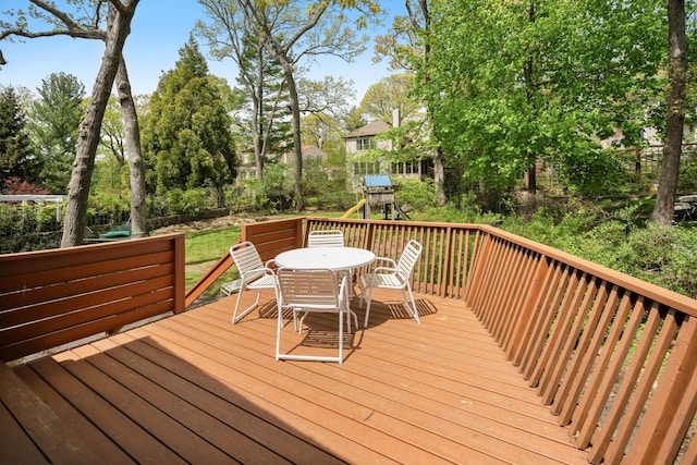 wooden deck featuring outdoor dining space and a playground