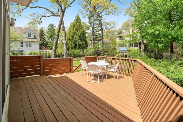 deck featuring outdoor dining space, a playground, and fence