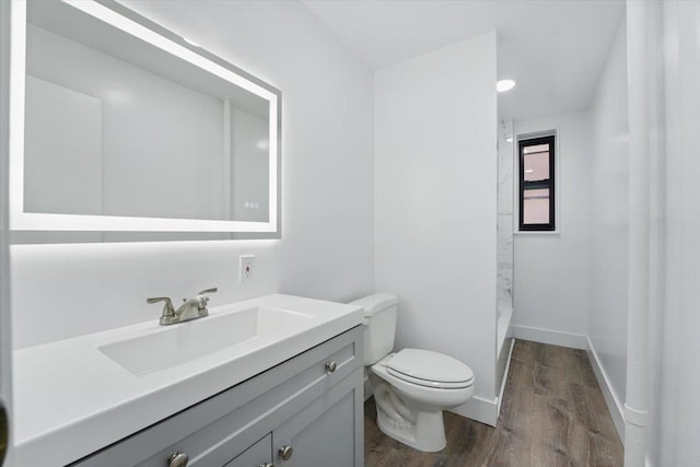 bathroom featuring wood finished floors, toilet, vanity, and a shower