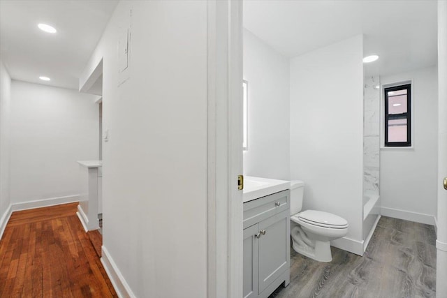full bathroom with toilet, wood finished floors, vanity, baseboards, and recessed lighting