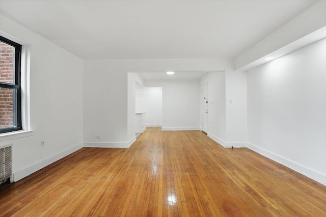 spare room with radiator, baseboards, and light wood-style floors