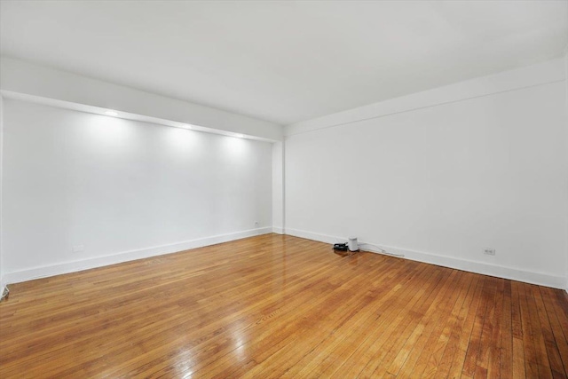 spare room with baseboards and light wood-style floors