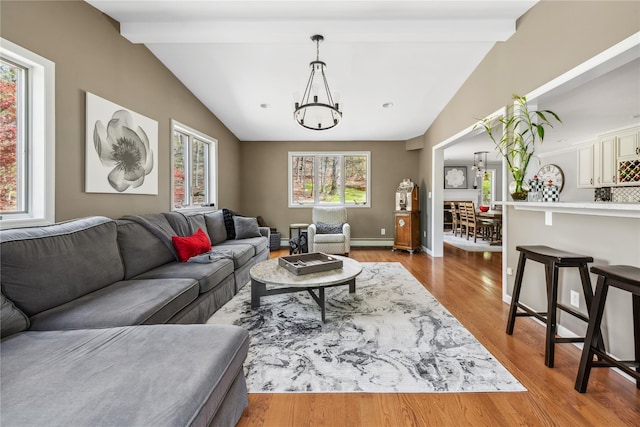 living room with wood finished floors, baseboards, a baseboard radiator, a chandelier, and vaulted ceiling with beams