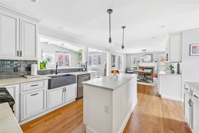 kitchen featuring stainless steel dishwasher, open floor plan, light wood-type flooring, white cabinets, and a sink