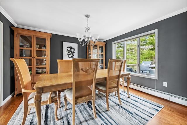 dining room with crown molding, wood finished floors, baseboards, a baseboard heating unit, and a chandelier